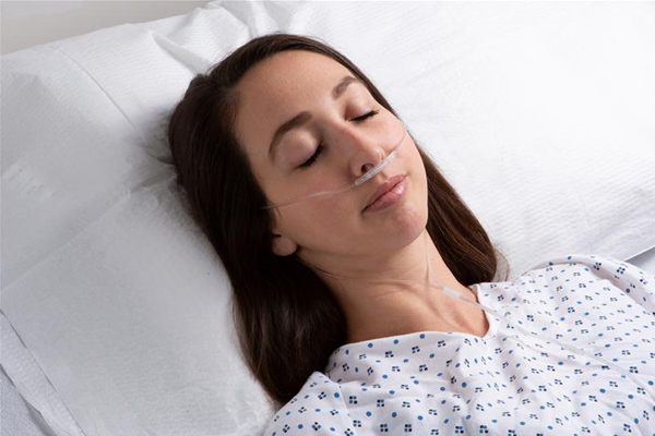 Adult sleeping wearing hospital gown.