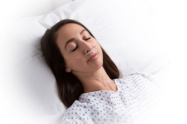Masimo – Femme adulte dans un lit d’hôpital avec la gamme Capnographie RRc de Nomoline
